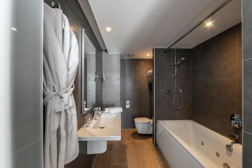 a bathroom with a tub and a sink and a toilet at Faros Hotel Ayia Napa in Ayia Napa