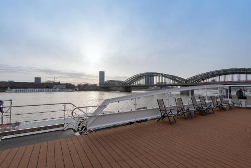 a boat on the water with a bridge in the background at Hotelship KD Moment Köln in Cologne