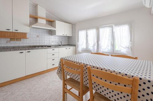 a kitchen with a table with chairs and white cabinets at Margherita Family Apartments in Cavallino-Treporti