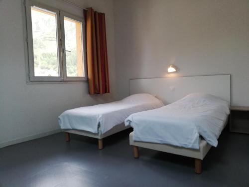 two beds in a room with a window at Village vacances de Val d'Isère in Val dʼIsère