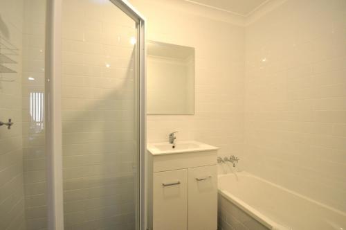 a white bathroom with a sink and a shower at Katoomba Townhouses in Katoomba