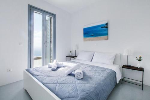 a white bedroom with a large bed and a window at The house of the setting sun in Apróvaton