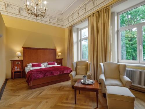 a bedroom with a bed and two chairs and a table at Hotel Marienhof in Reichenau