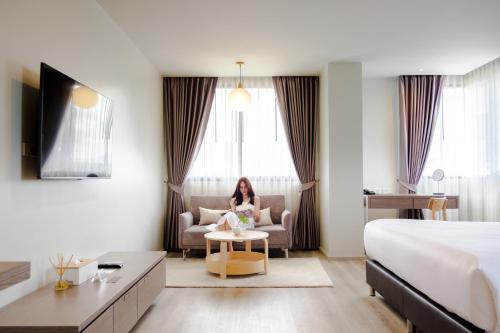a woman sitting in a chair in a hotel room at The Rise Suites Hotel, Chiang Mai - SHA Extra Plus in Chiang Mai