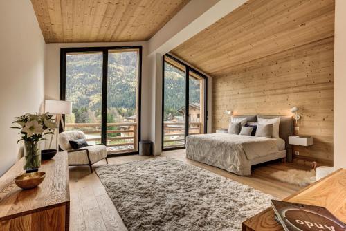 une chambre avec un grand lit et de grandes fenêtres dans l'établissement La Cordee 221 Penthouse - Chamonix All Year, à Chamonix-Mont-Blanc
