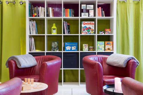 two chairs and a book shelf with books at Comfort Hotel Grenoble Meylan in Meylan