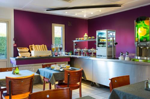 a restaurant with purple walls and a counter and tables at Comfort Hotel Grenoble Meylan in Meylan