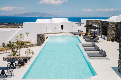 a beach area with a pool, chairs, and a balcony at Secret View Hotel in Oia