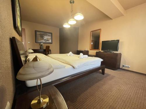 a hotel room with a large bed and a television at Penzion Benedikti in Prievidza