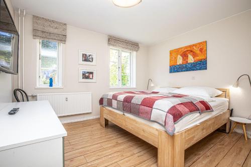 a bedroom with a bed and a desk and two windows at fewo1846 - Gerty Molzen - komfortable 2-Zimmer-Wohnung mit Terrasse im Stadtzentrum in Flensburg