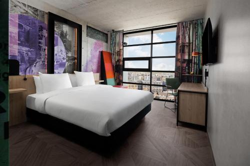 - une chambre avec un grand lit et une grande fenêtre dans l'établissement Inntel Hotels Amsterdam Landmark, à Amsterdam