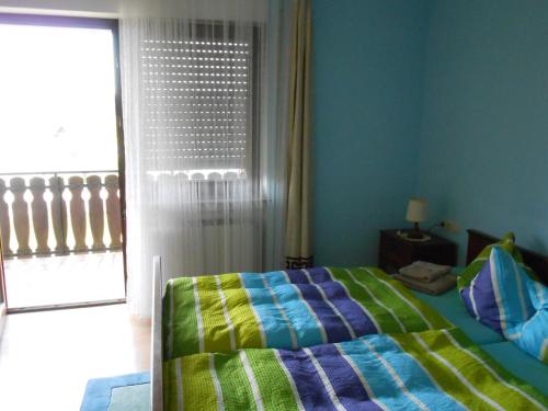a bedroom with a bed with a colorful comforter and a window at Pension Weinhaus Unger in Schwenningen