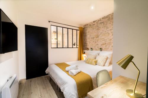 a bedroom with a bed and a table with a lamp at Appartement Cosy Nîmes-Centre in Nîmes