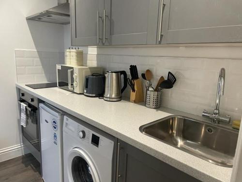 a kitchen with a sink and a washing machine at Queen Street Apartments in Wolverhampton