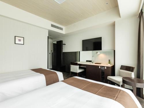 a hotel room with two beds and a desk at Tenza Hotel at Hakata Station in Fukuoka