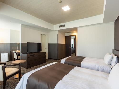 a hotel room with two beds and a flat screen tv at Tenza Hotel at Hakata Station in Fukuoka