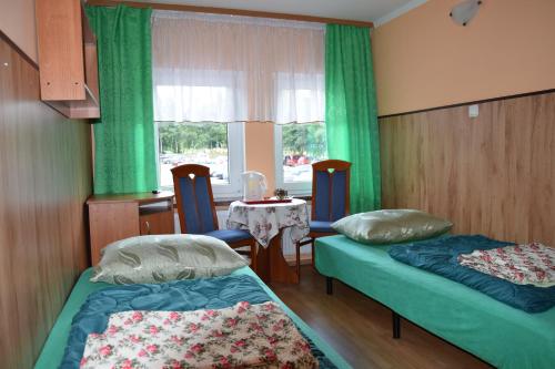 um quarto com duas camas e uma mesa e uma janela em Ośrodek Wypoczynkowy Pod Szczelińcem em Karłów