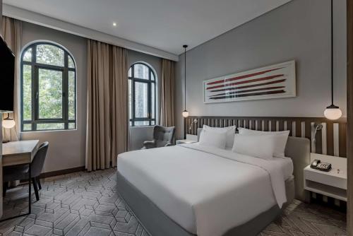 a bedroom with a large white bed and a desk at Radisson Lagos Ikeja in Lagos