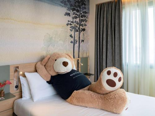 a large teddy bear is sitting on a bed at Novotel Madrid City Las Ventas in Madrid