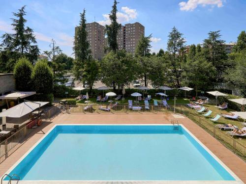 a large swimming pool with chairs and umbrellas at Novotel Milano Nord Ca' Granda in Milan