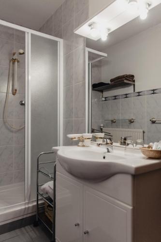 une salle de bain blanche avec un lavabo et une douche dans l'établissement Hôtel Les Charmilles de Mormal, à Landrecies