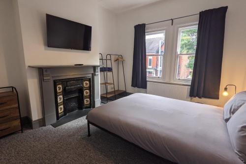 a bedroom with a bed and a fireplace with a flat screen tv at Linthorpe Terrace in Middlesbrough