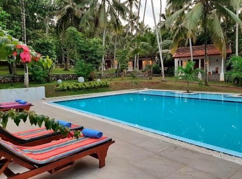 a swimming pool with two lounge chairs and a house at Jackland Holiday Cabanas in Demanhandiya