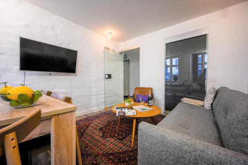 a living room with a couch and a tv on a wall at Lake - Pleasant 2-Bdr Apt in City Center in Copenhagen