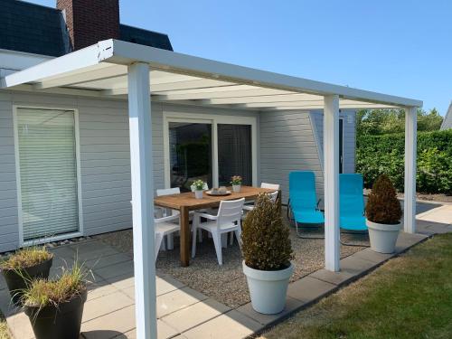 a pergola on a patio with a table and chairs at Kustverhuur, Park Schoneveld, Zeester 25 in Breskens
