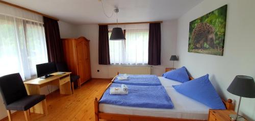 Schlafzimmer mit einem Bett mit blauer Bettwäsche und einem Schreibtisch in der Unterkunft Grüner Baum in Neckargerach