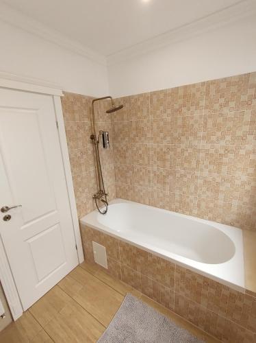 a white bath tub in a bathroom with a door at Fanea Residence in Timişoara