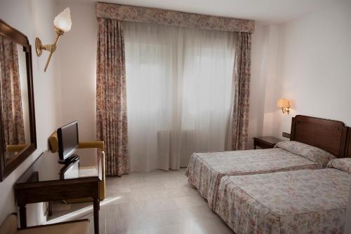 a hotel room with two beds and a television at Hotel Juanito in Baeza