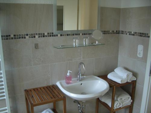 een badkamer met een wastafel, een spiegel en handdoeken bij No Beach in Solingen