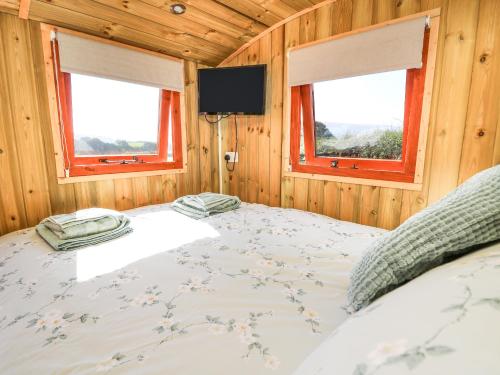 a bed in a wooden room with two windows at Claerwen in Llandrindod Wells