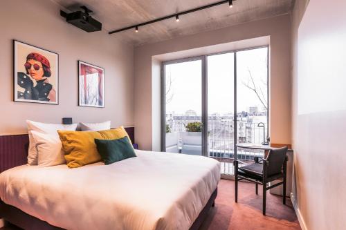 Hotel Paradiso في باريس: غرفة نوم بسرير وكرسي ونافذة