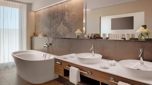 a bathroom with two sinks and a bath tub at Hotel Stadt Lörrach in Lörrach