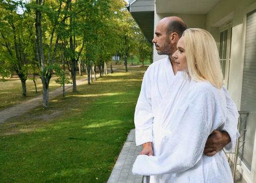 a man and a woman standing outside of a house at Sanatorija ,,Tulpės" in Birštonas