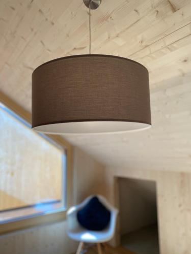 a lamp hanging from a ceiling with a blue chair at SMART Apartments Mellau in Mellau