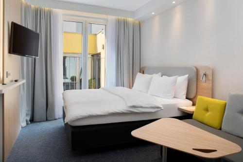 um quarto de hotel com uma cama e um sofá em Holiday Inn Express Baden-Baden, an IHG Hotel em Baden-Baden