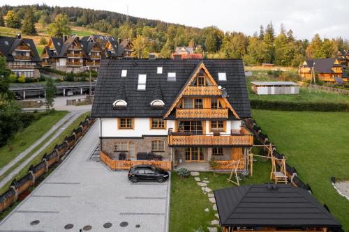 dom z samochodem zaparkowanym przed nim w obiekcie Apartamenty Franka Zakopane w mieście Kościelisko
