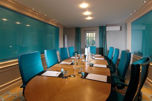 a conference room with a long table and blue chairs at Royal Berkshire in Ascot