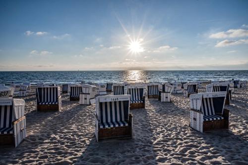 rząd leżaków na piaszczystej plaży w obiekcie Wohnung West w mieście Westerland