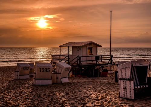 stacja ratownicza na plaży o zachodzie słońca w obiekcie Wohnung West w mieście Westerland