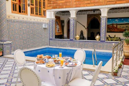 a table with plates of food sitting on a patio at Riad Sayeda Al Hora in Fès