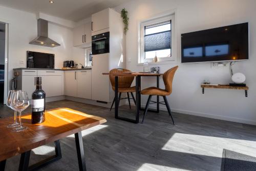 a kitchen and living room with a table with a bottle of wine at At Sea Zoutelande - Nieuwstraat 15a in Zoutelande
