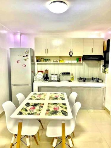 a kitchen with a table and chairs and a refrigerator at Cozy Central - Near arca south signal taguig in Manila