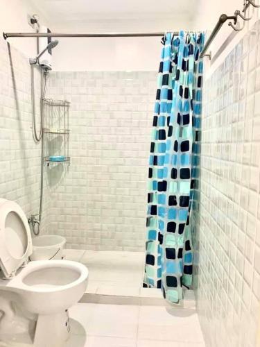 a bathroom with a toilet and a blue shower curtain at Cozy Central - Near arca south signal taguig in Manila