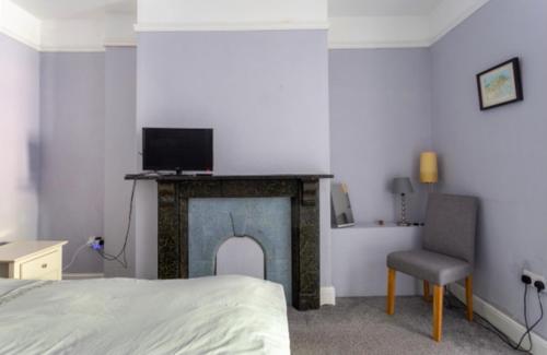 a bedroom with a fireplace and a bed and a chair at Bridport Garden Suite in Bridport