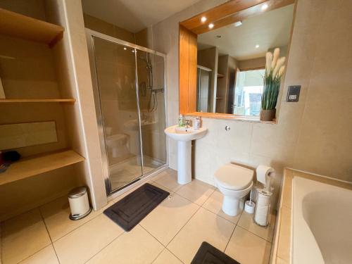 La salle de bains est pourvue d'une douche, de toilettes et d'un lavabo. dans l'établissement City Centre 2-Bed Apartment Parking Jacuzzi Bath, à Glasgow