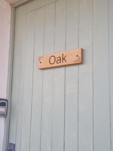 a wooden sign that reads oak hanging on a wall at Oak, Country chalet located in Pegsdon in Hexton